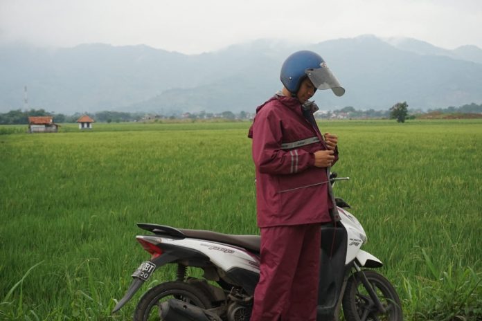 Menggunakan Jas Hujan